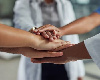 Closeup shot of an unrecognizable group of medical practitioners putting their hands together in a huddle