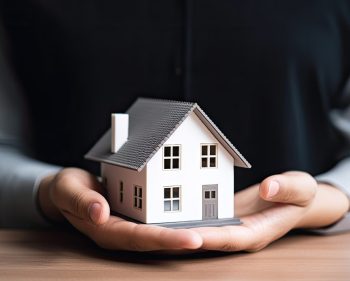 woman showing with one hand a mini house. Real state concept.